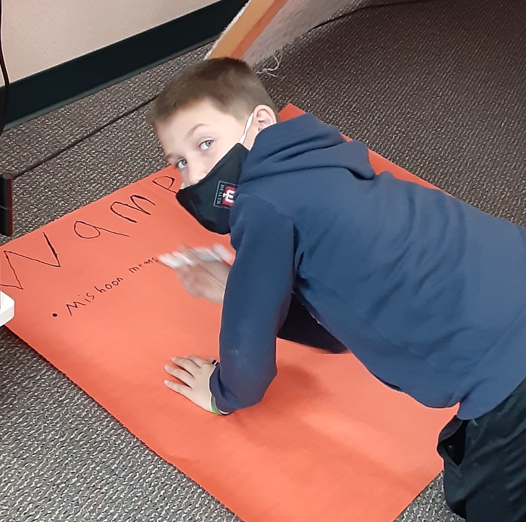 Boy turning around to look at the camera as he works on a poster
