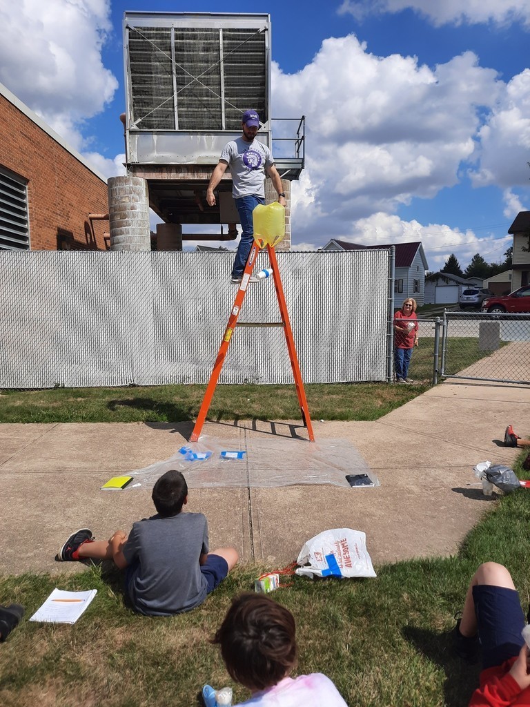 Teacher stands atop a ladder to drop egg