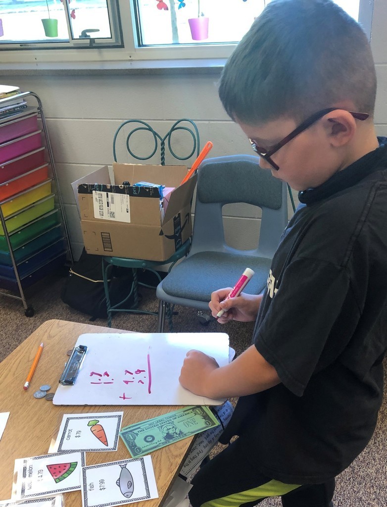 Boy works on math problem with a pink marker