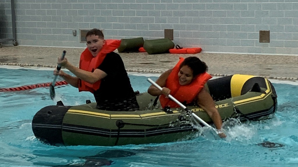 2 students  rowing a raft in the pool