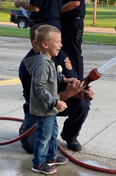 Pre-school student holds fire hose