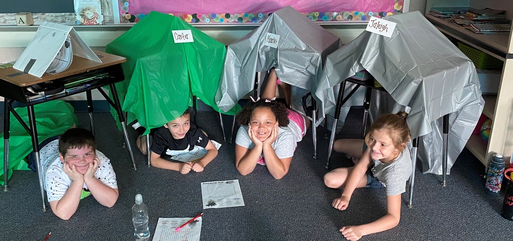 2nd graders work on homework under tents