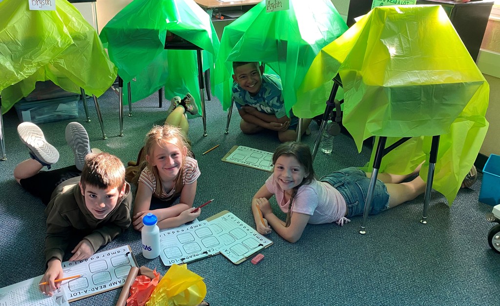 3 smiling 2nd graders working on tents