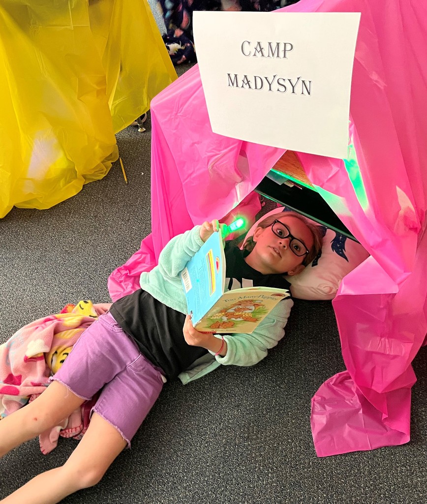 girl reads a book in her classroom tent