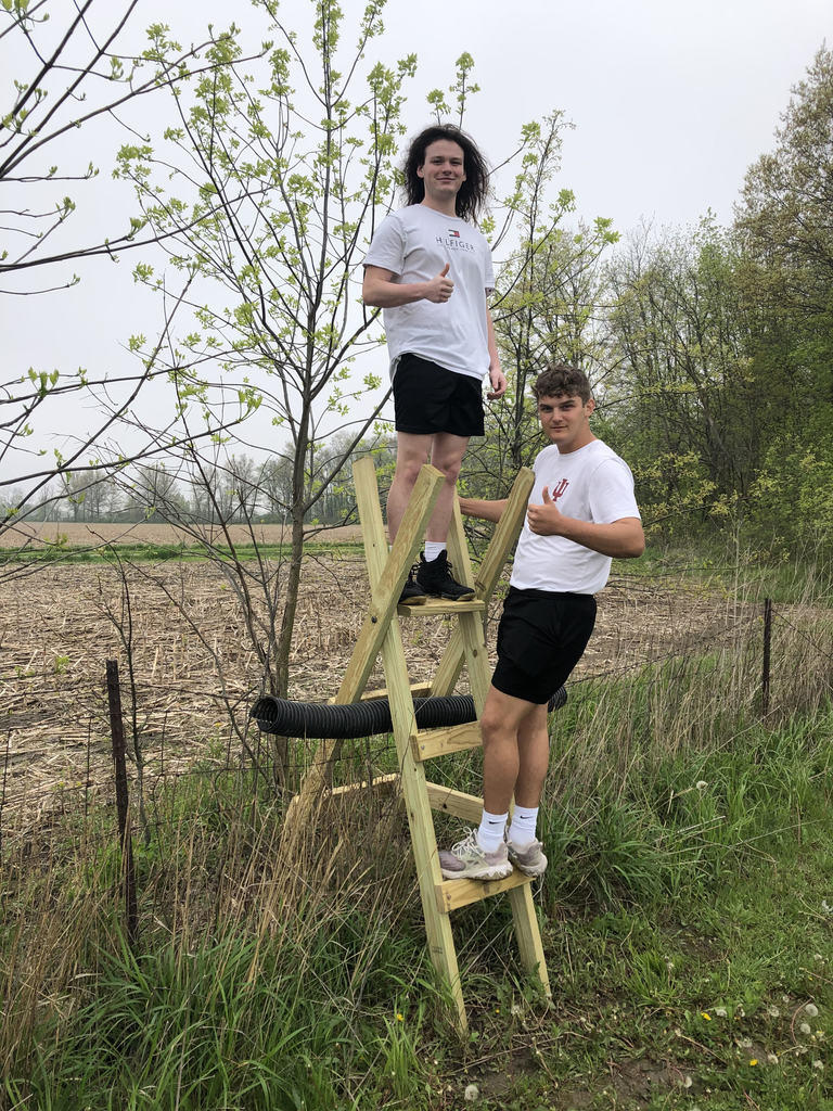 Two students use the step ladder they made in manufacturing class