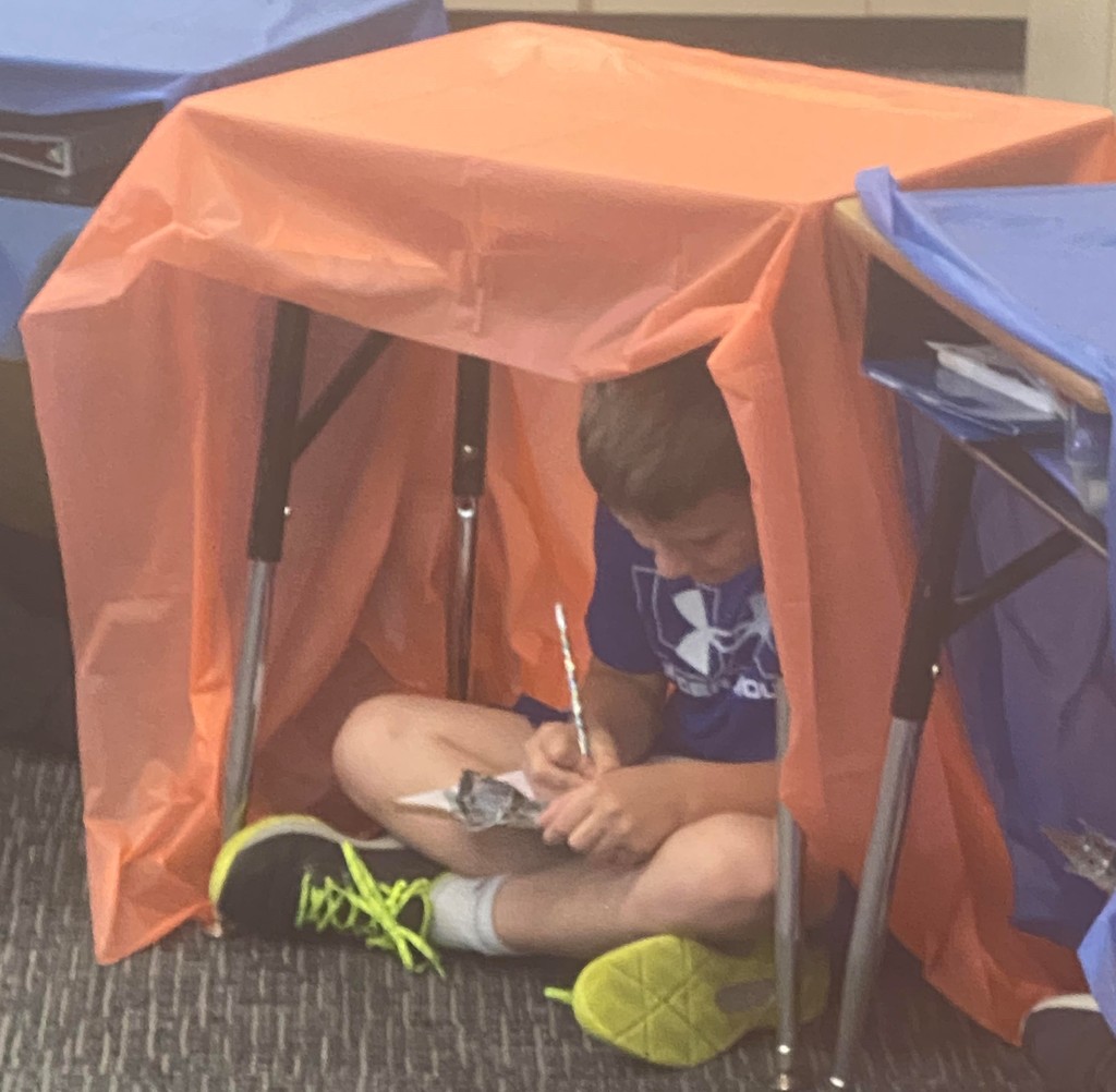 boy sits under his tent desk